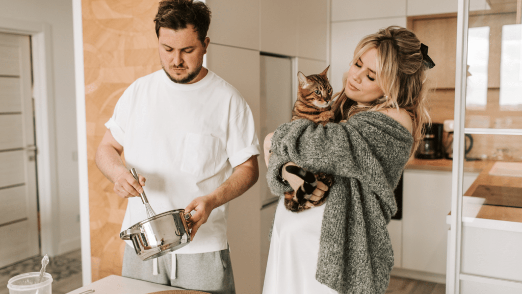 A couple holding a cat in their living room