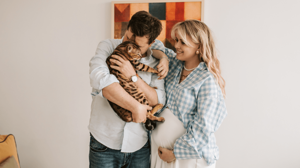 A couple holding a cat in their living room