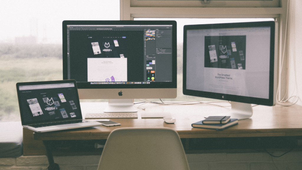 a desk with three computers and a laptop on it