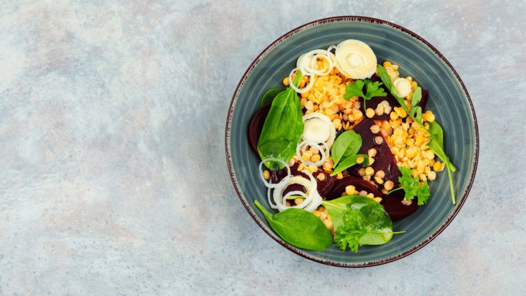 a salad with beets, apples and greens on a black plate